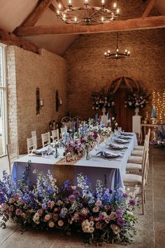 a long table set up with flowers and candles for a wedding reception in an old building