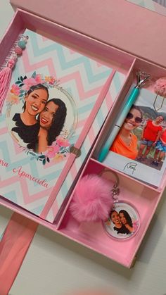 an open pink box with pictures and keychain on the inside that is decorated with tassels