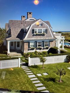 a large white house sitting on top of a lush green field next to a swimming pool