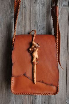 a brown leather bag with a wooden cross on it