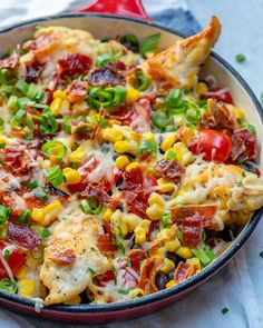 a skillet filled with chicken, corn and vegetables