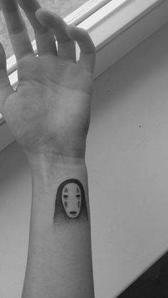 a person with a tattoo on their wrist holding up a hand in front of a window