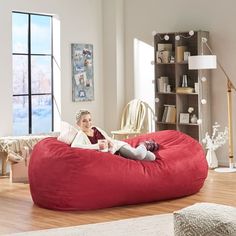 a woman is sitting on a large red bean bag chair in the middle of a living room