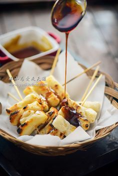 food is being drizzled with sauce in a basket on a wooden table