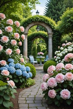 a garden with pink and blue flowers on the ground, in front of an archway