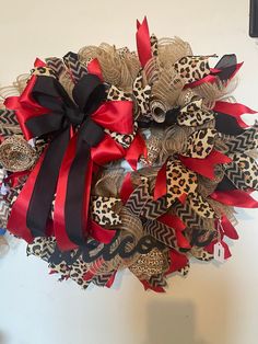 a leopard print wreath with red and black ribbons on the front door, hanging on a wall