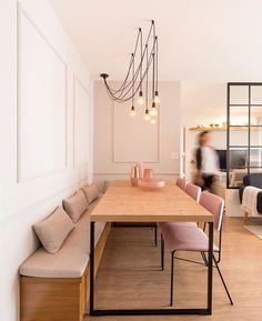 a dining room with a bench and some lights hanging from it's side wall