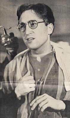 an old black and white photo of a man with glasses holding something in his hand