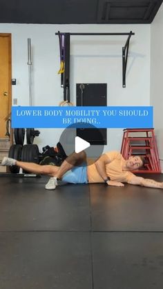 a man laying on the ground in a gym with his leg up and another man standing behind him