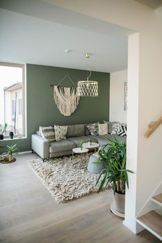 a living room filled with furniture next to a stair case and potted plant on top of a rug