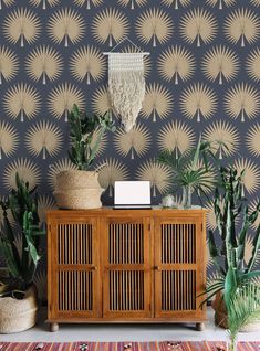 a wooden cabinet sitting in front of a wall with plants on it