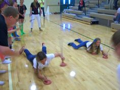 some kids are playing on the floor in a gym