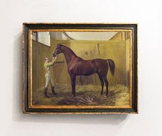 a man standing next to a brown horse in a barn with hay on the ground