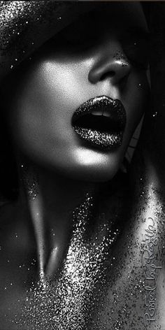 a black and white photo of a woman's face with glitter on her body