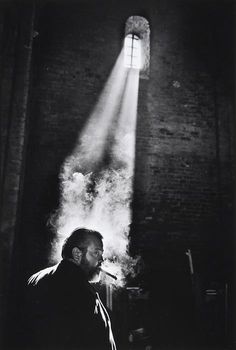 a man standing in front of a brick wall with a light coming from the window