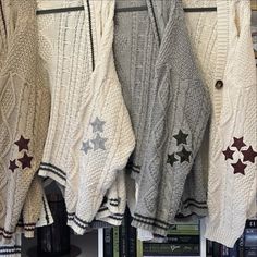 several sweaters hanging up on a rack in a room with books and other items