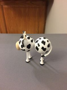 two black and white cow figurines sitting on top of a gray tablecloth