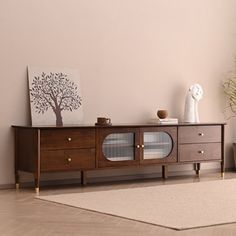 a living room with a wooden entertainment center and potted plants on the sideboard