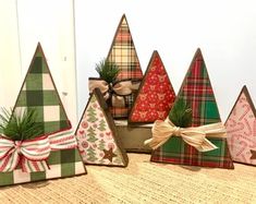 small christmas trees are lined up on a table with bows and ribbons around them,