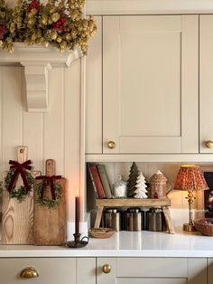 a kitchen with white cabinets and christmas decorations on the counter top, along with candles