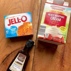 two boxes of jello and an orange juice on a wooden table next to each other