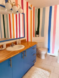 a bathroom with multicolored stripes painted on the walls and wooden counter tops, along with a toilet