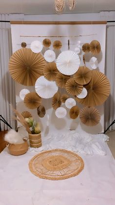 an arrangement of paper fans is displayed on a white sheeted backdrop in front of a chandelier