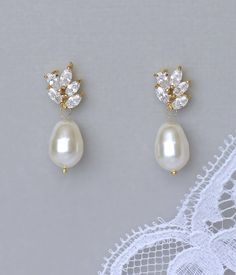 two pairs of pearl and crystal earrings on top of a white lace doily,