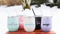 four different colored tumblers with straws in them on top of a wooden table