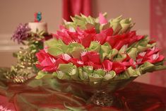 a vase filled with red and green flowers on top of a cloth covered tablecloth