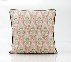 a pink and green pillow sitting on top of a white table