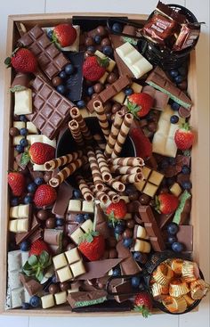 a box filled with lots of different types of chocolates and strawberries on top of it