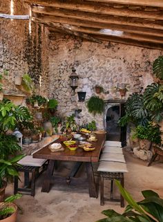 an outdoor dining area with potted plants and stone walls