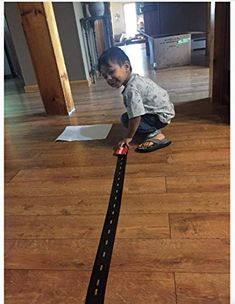 a young boy playing with a toy train on the floor