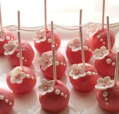 red cake pops decorated with white flowers on a platter, ready to be eaten