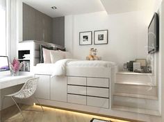 a bedroom with white furniture and pictures on the wall, along with a small desk