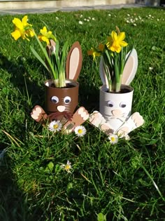 two bunny planters sitting in the grass with daffodils