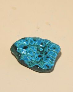 a piece of blue glass sitting on top of a white table next to a brown wall