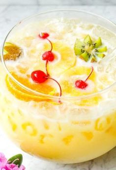 a close up of a drink in a glass on a table with flowers around it