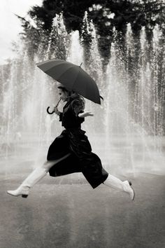 a woman is jumping in the air with an umbrella over her head while holding an umbrella