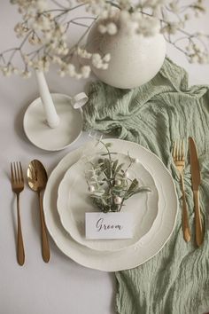 a table setting with place cards, silverware and flowers in a vase on top