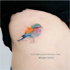 a colorful bird tattoo on the back of a woman's stomach