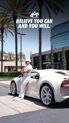 a man sitting on the back of a white sports car in front of a building