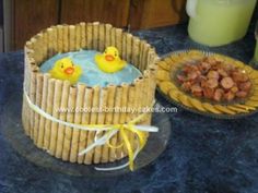 a cake made to look like two rubber ducks in a bathtub with food on the side