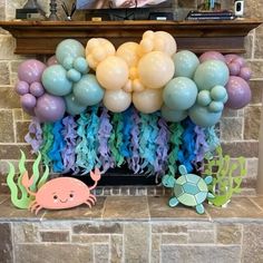 an under the sea birthday party with balloons, streamers, and decorations on a fireplace mantel