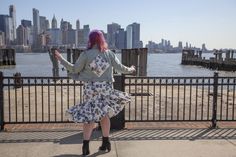 a woman with pink hair is standing by the water