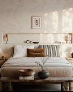 a bedroom with a bed, nightstands and pictures on the wall above it in shades of brown and white