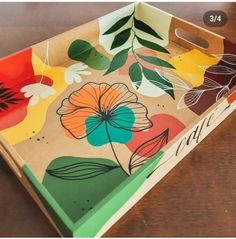 a wooden tray with flowers painted on the sides and leaves drawn on the inside, sitting on a table