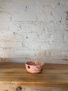 a pink and white bowl sitting on top of a wooden table