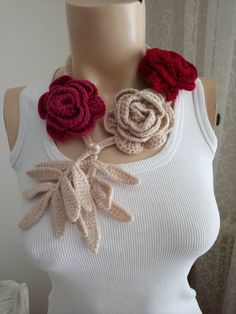 a woman wearing a white tank top with crocheted flowers on it's neck